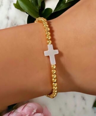bracelet femme perles dorées avec croix blanche centrale, bijou fantaisie minimaliste chic sur poignet élégant, parfait en superposition ou porté seul